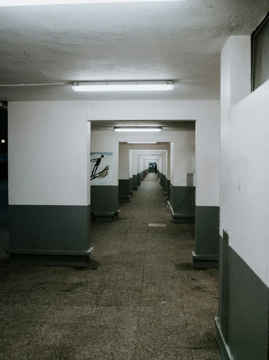 a long hallway with several sinks and a painting on the wall