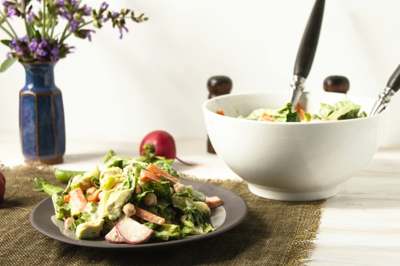 a plate topped with salad next to a bowl of salad