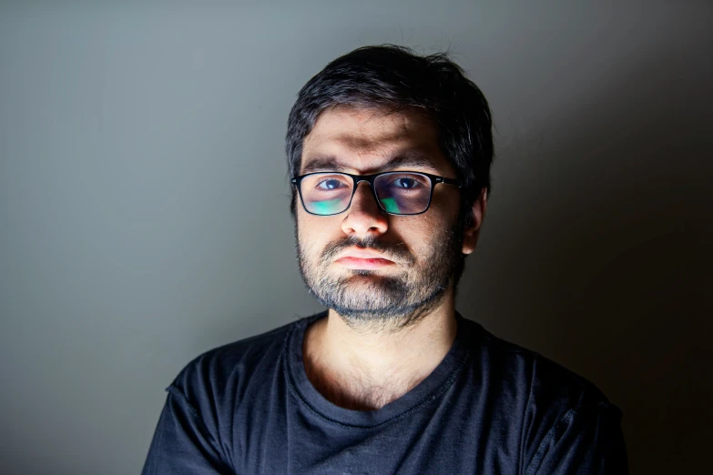 a man with dark hair and glasses is looking away from the camera