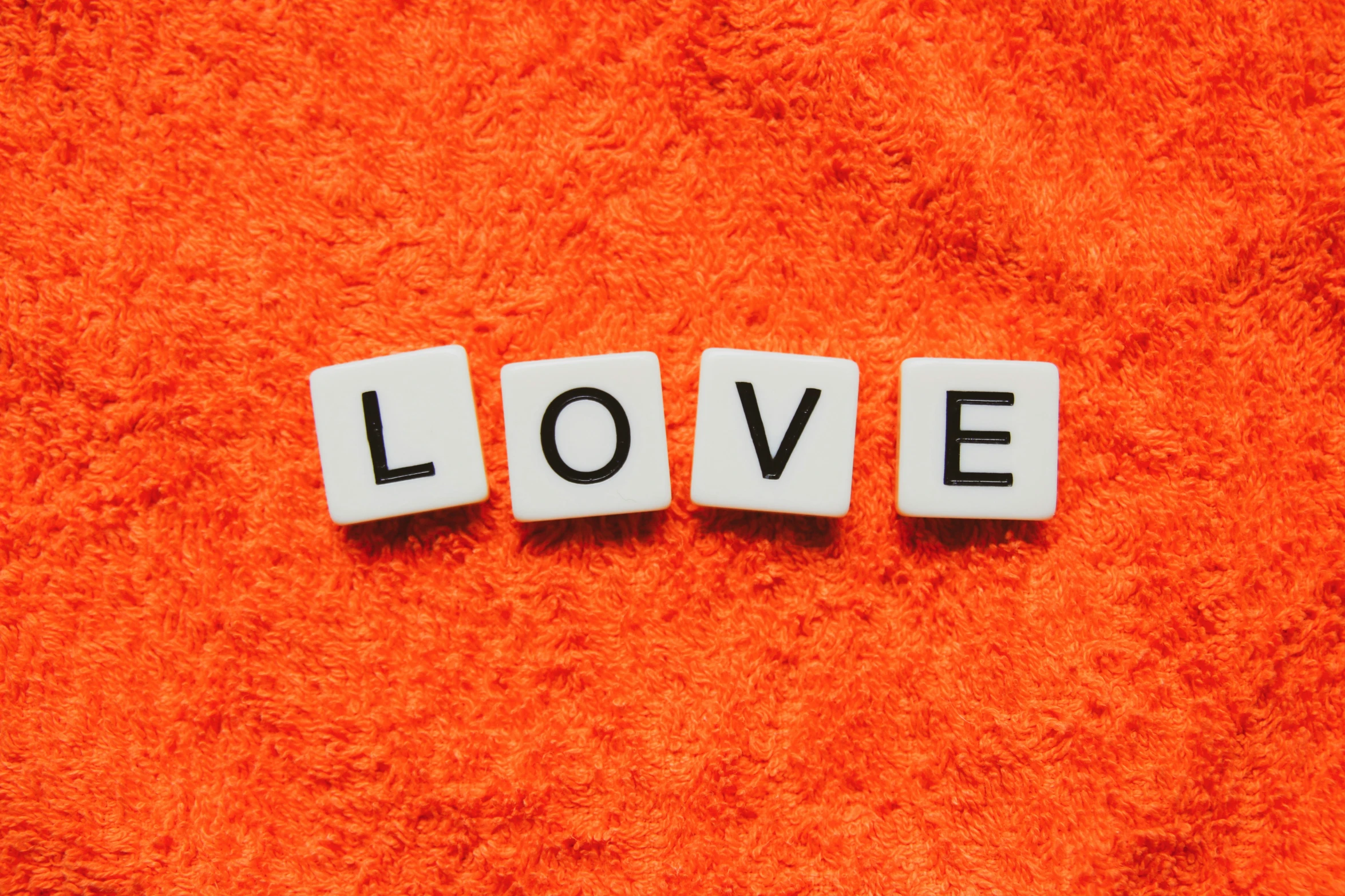 the letters love spelled in small tiles on an orange carpet