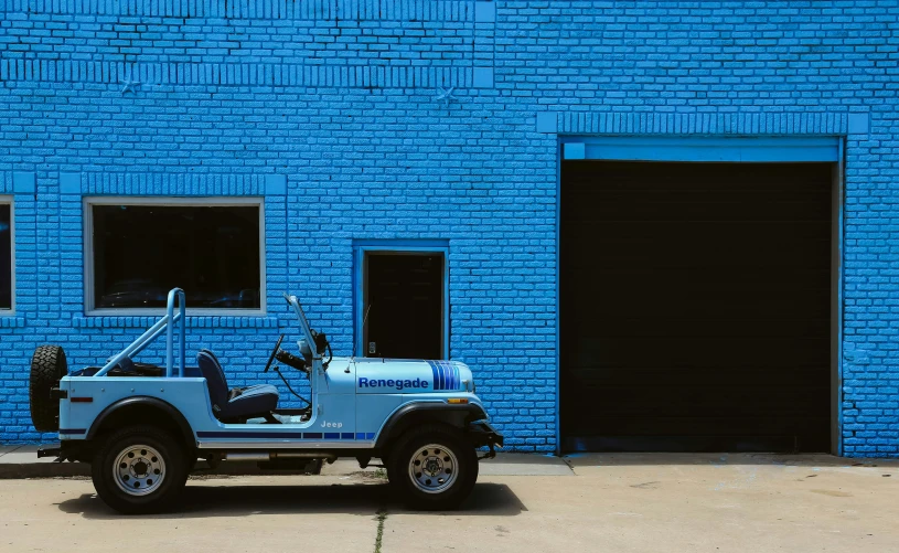 the jeep is parked outside of the bright blue brick building