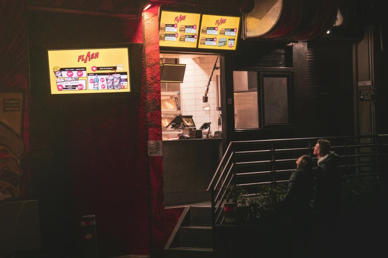 people are sitting and eating outside a fast food shop