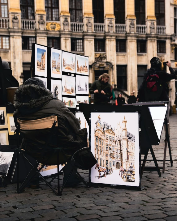 a person sitting on a chair in front of art work