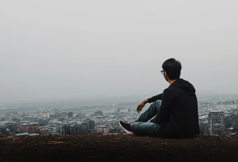 a person sitting on the top of a hill overlooking a city