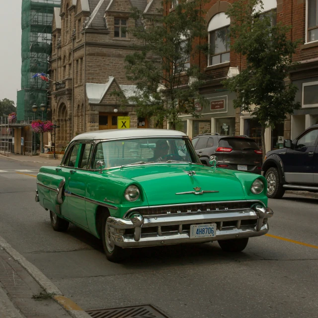 an old fashioned green car driving on the road