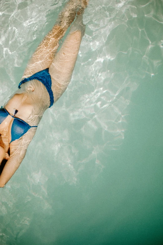 woman in bikini swimming on a blue board