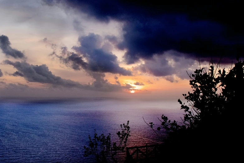 sunset in the background and dark clouds over the water