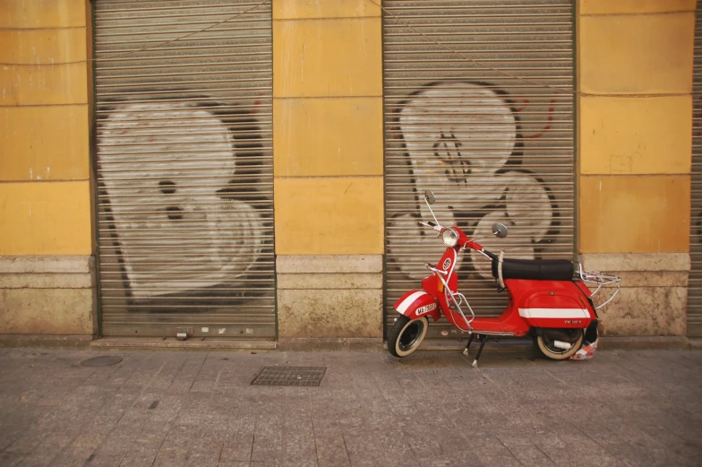 a scooter sitting next to a wall with faces painted on it