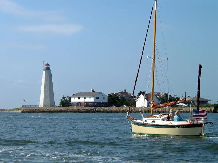 a sail boat sails across the ocean and next to a light house