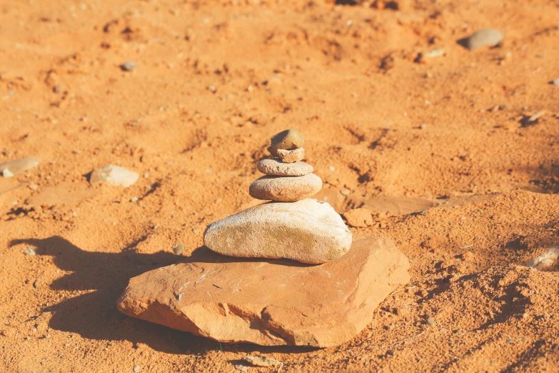 a stack of rocks on top of a red dirt ground