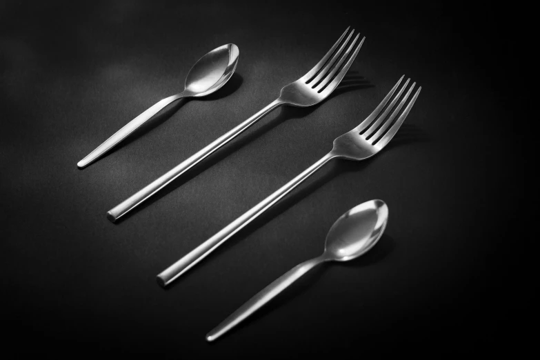 three forks and a knife on a black surface