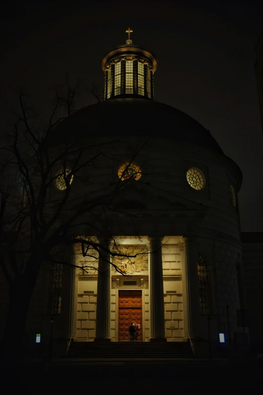 an old round church building at night with a bright red door
