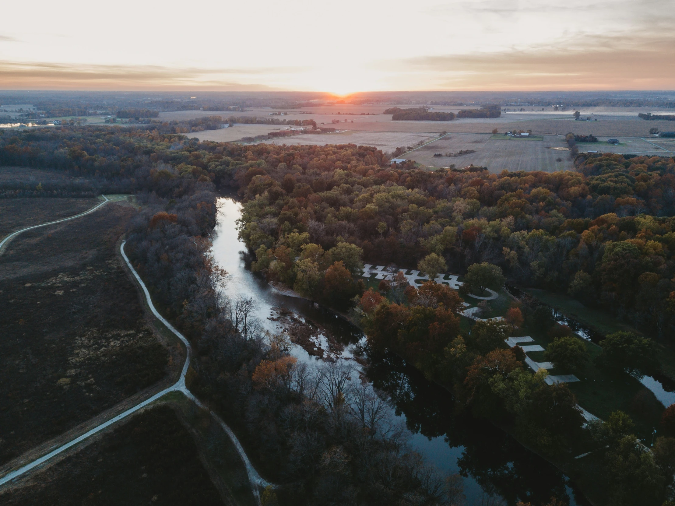 a river flows under the setting sun next to a forest