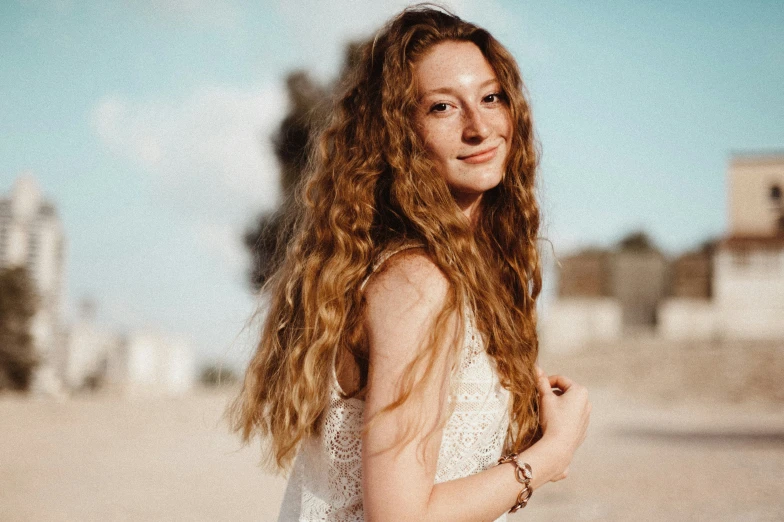 a woman wearing a white dress standing on the beach