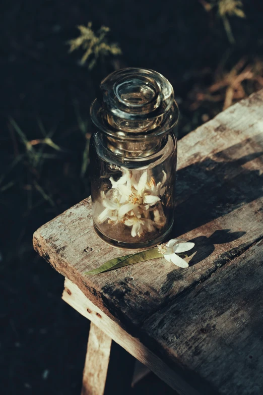 small clear jar full of flowers sitting on a table