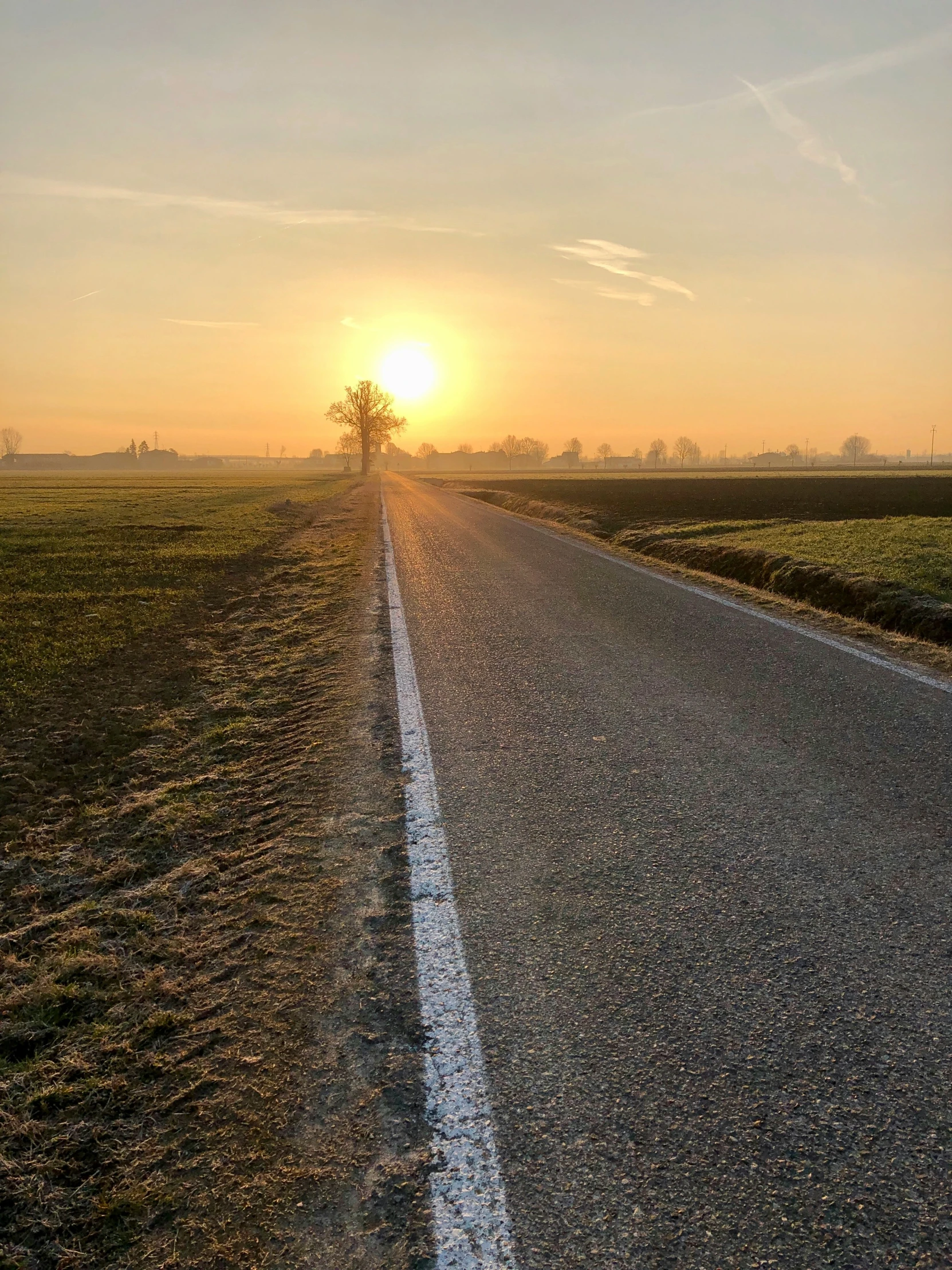 the sun setting over the top of a lonely rural road