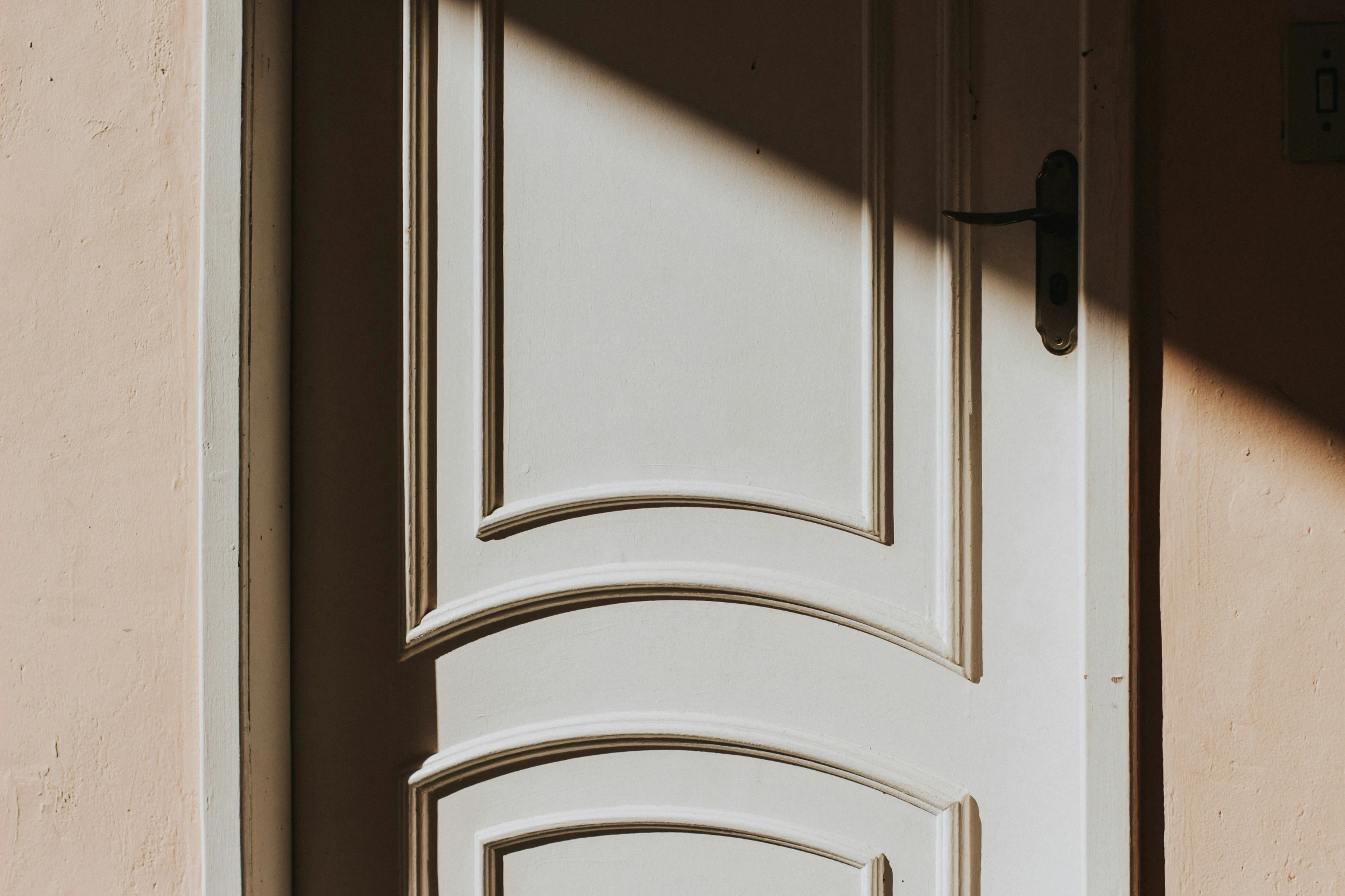 an arched white door that is opened and light filtering