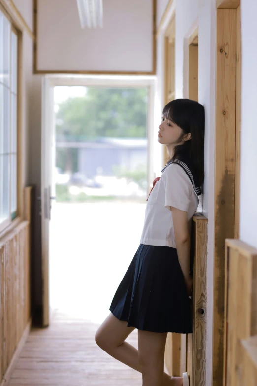 a girl leans against the side of a door way