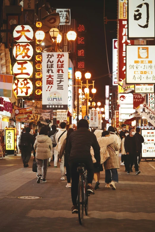 a bicyclist passing through an asian city at night