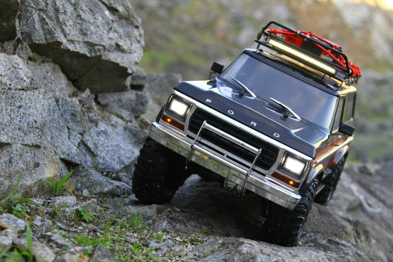 a toy truck riding on some rocks on the side of a mountain