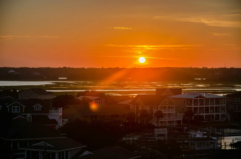 a colorful sunset in the background with buildings and homes