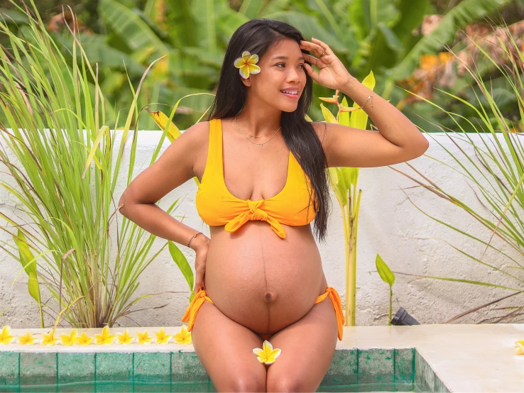 a beautiful woman in a yellow bikini standing near a pool