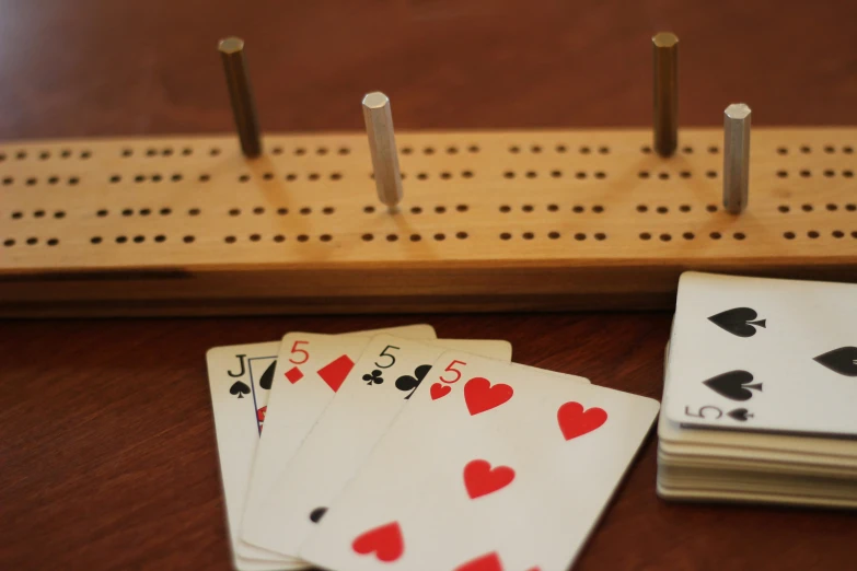 four decked up playing cards sit on top of two peg boards