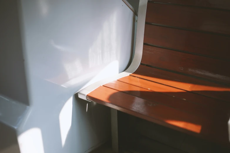 a wooden bench next to a white wall