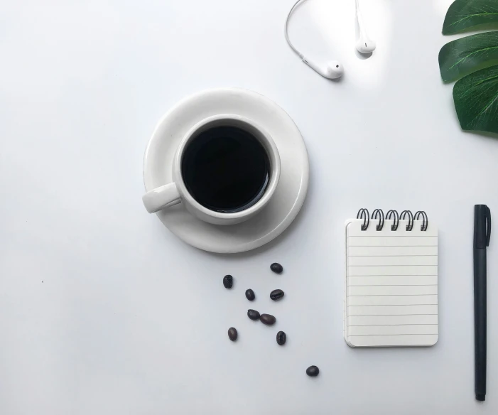 the white table has notebooks and a cup of coffee next to it