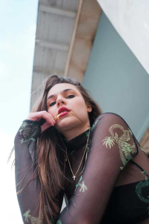 woman in black sheer mesh shirt leaning against building