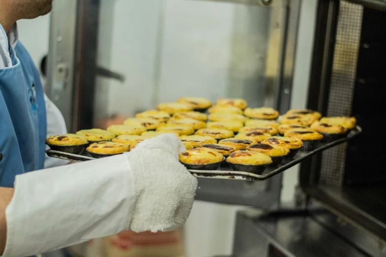 a man cooking pastries inside of a commercial oven