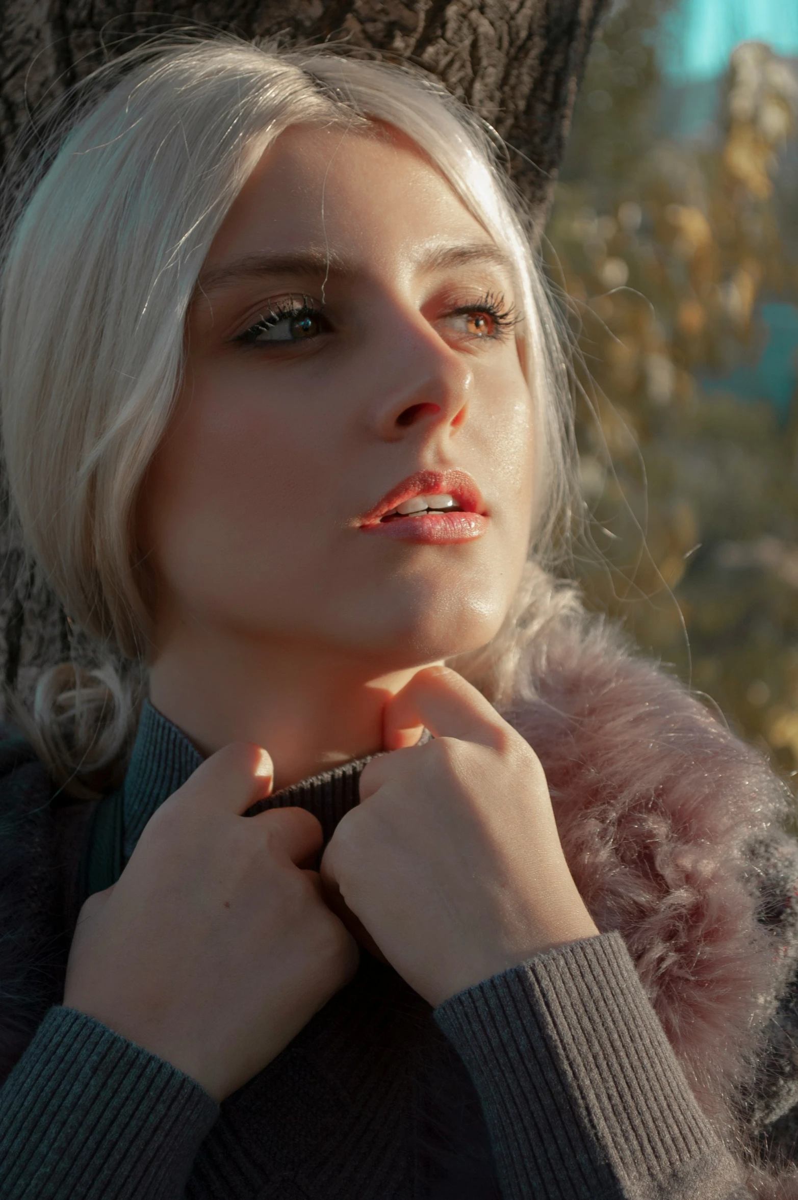 an attractive blond woman poses by a tree