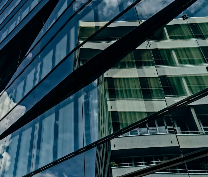 some glass windows on a building with clouds in it