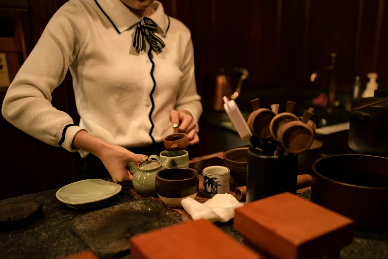 a woman standing over a table filled with cups