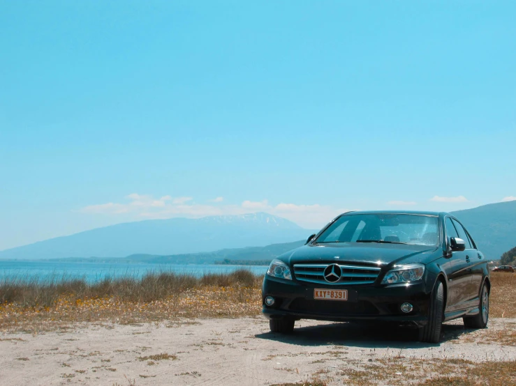 a mercedes benz is parked on the side of a road near water