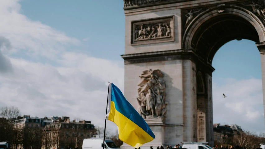 flag flying in front of a monument with a sky background