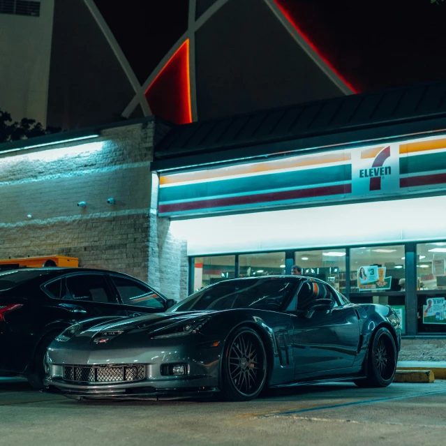 two different colored cars sit in front of a restaurant