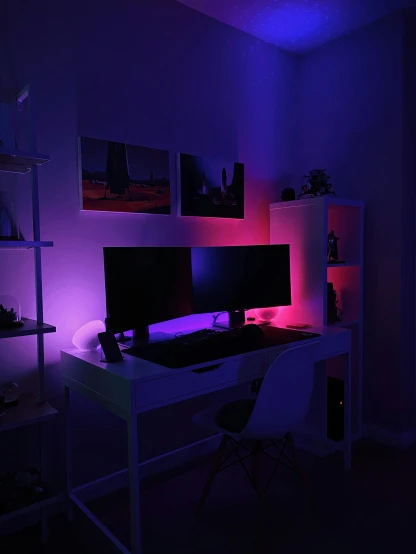 a computer desk with an illuminated monitor in the dark