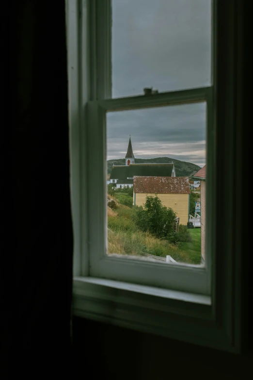 a view out the window of an old house looking at a small village