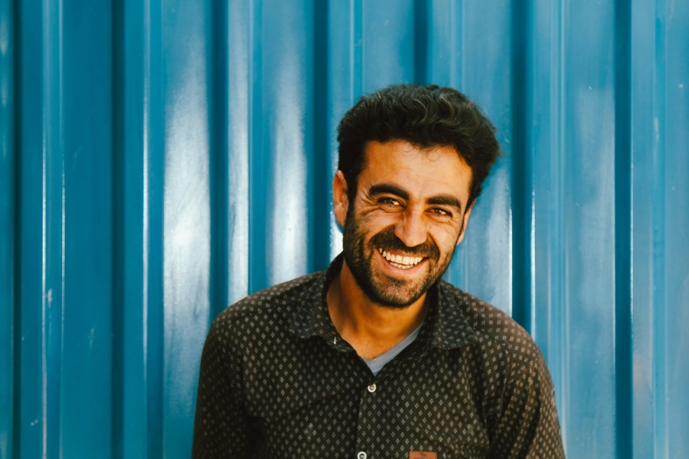 a man poses for a picture in front of a blue wall