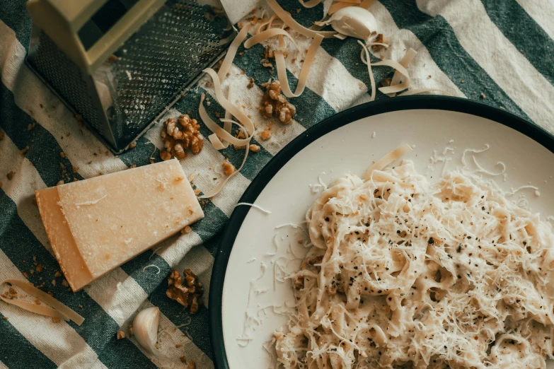 a plate full of pasta and cheese next to some grated cheese