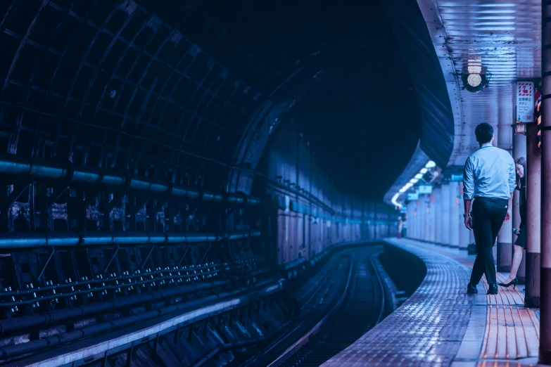 a person standing in a train station while looking at soing