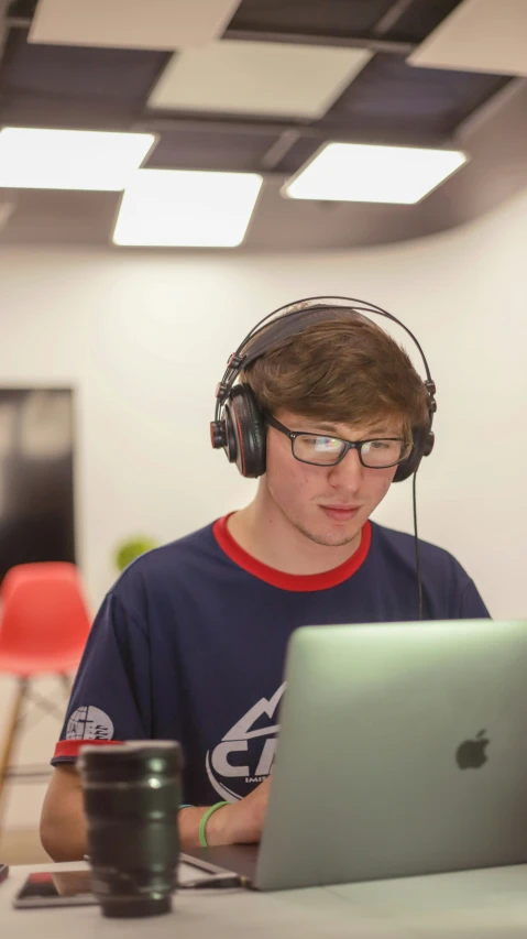 a  wearing headphones and holding an open laptop