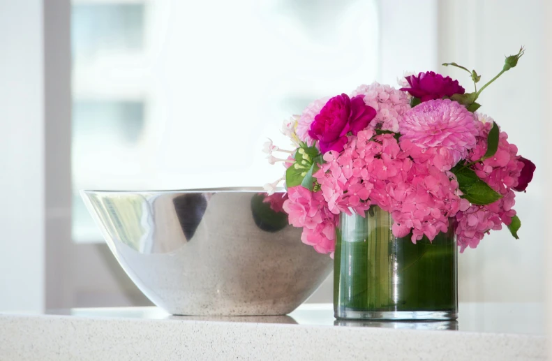 flowers are in a silver vase, near a metal bowl