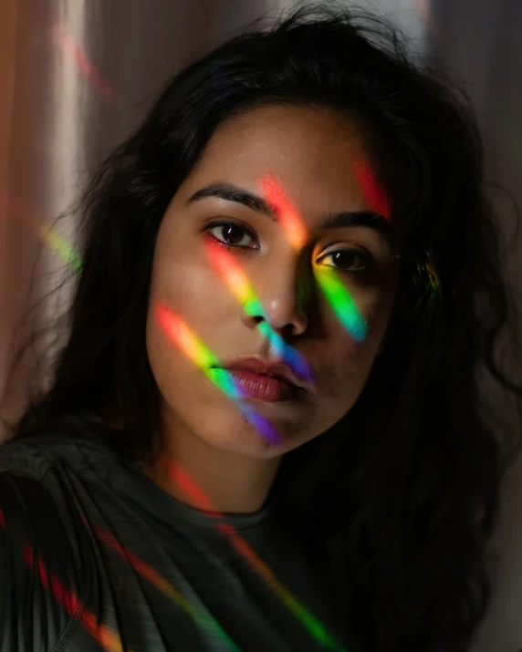 woman wearing eyeliners and rainbow light in front of a curtain