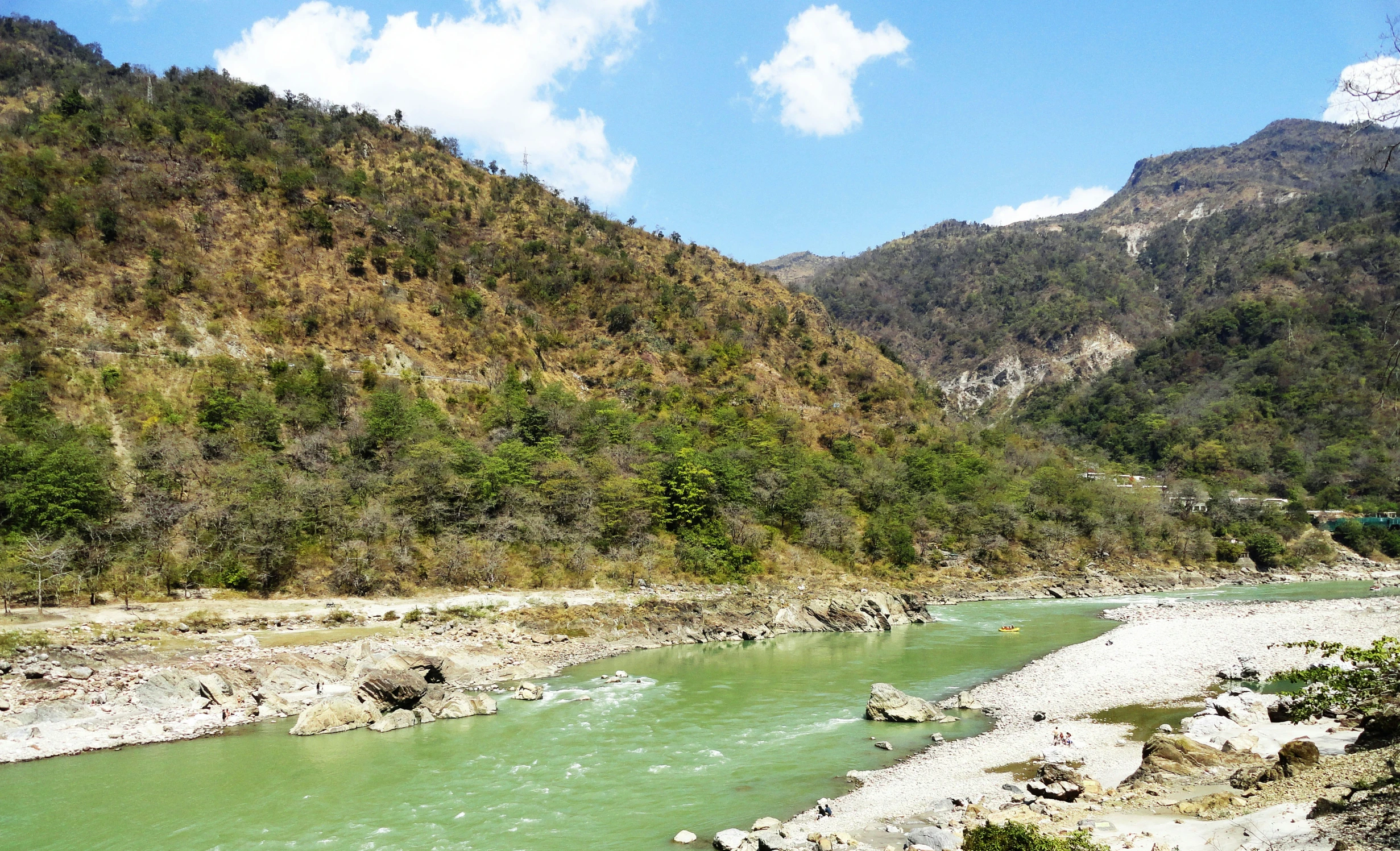 river running through the mountains under blue sky