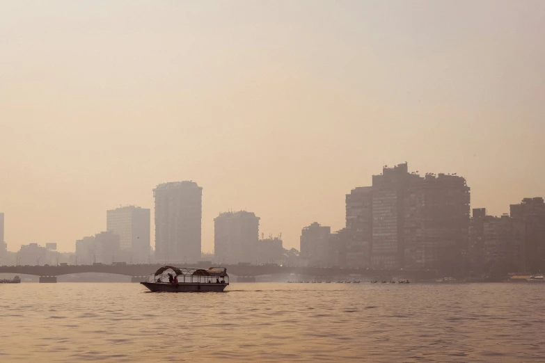 a small boat in the water with city in background