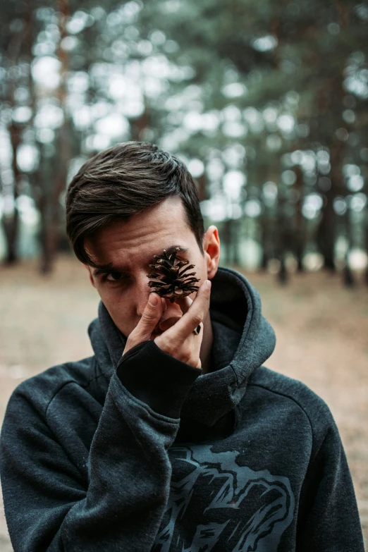 a man in a black hoodie standing in the woods