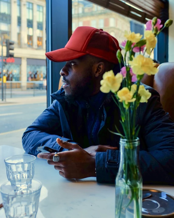 man in red cap sitting at table in cafe