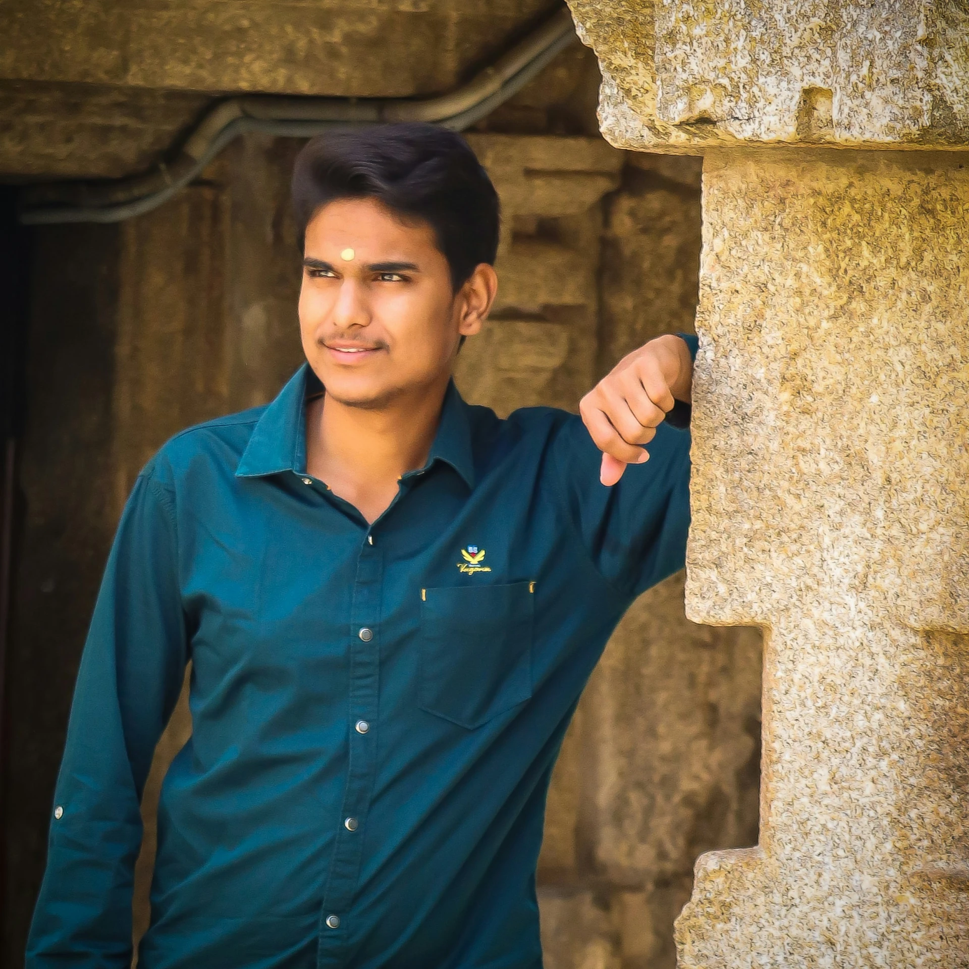 a man standing next to a stone pillar